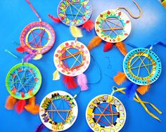 paper plate crafts are arranged on a blue surface with colorful feathers and arrows in the center