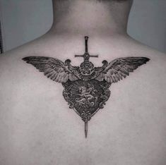 the back of a man's chest with a cross and wings on top of it