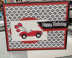 a handmade birthday card with a red car and balloons on the front, sitting on top of a table