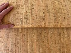 a close up of a person's hand on a piece of cork