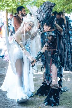 two cosplayers dressed in costumes standing next to each other on the ground