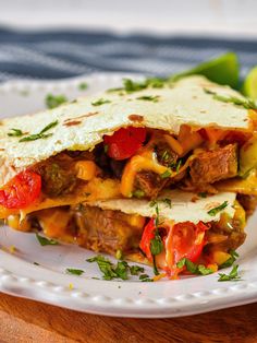 two quesadillas stacked on top of each other with tomatoes, peppers and cheese