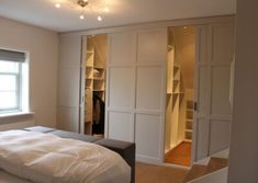 an empty bedroom with white walls and closets in the corner, as well as a bed