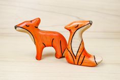 an orange and white fox figurine sitting on top of a wooden table next to another animal