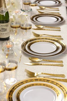 the table is set with gold and white plates, silverware, and champagne bottles