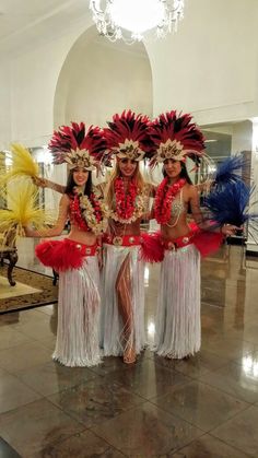 three women dressed in red and white hula skirts, with their arms around each other