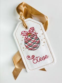 a christmas ornament hanging from a gold ribbon on a white background with the word steve written across it