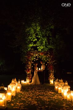 a bride and groom standing in front of lit candles