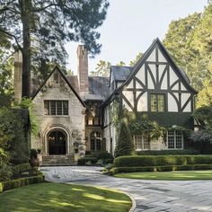 a large house that is in the middle of some trees and grass with bushes around it