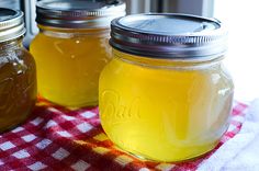 three jars filled with liquid sitting on top of a red and white checkered table cloth