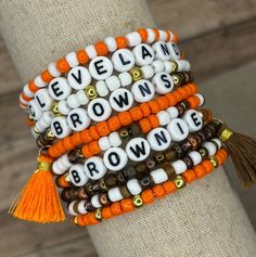 The ultimate bracelet listing for any Cleveland Browns fan! Go Brownies! These bracelets are SOLD INDIVIDUALLY unless purchased as a STACK! If wanting multiple bracelets, please add each one individually to your cart! Bracelets with letter beads can be personalized to exchange for a different word/name or player number. Please use the personalization box if wanting this; otherwise, your bracelet will come as pictured! We use Czech glass beads and a combination of 18k gold plated beads and galvanized gold beads. Bracelets come in sizes 6"-8". If you are needing a more personalized size, please reach out to us! Please see our sizing notes and care instructions included in our photos. Following these instructions can ensure the best fit for you and longevity of your bracelets!  Hey! While you White Personalized Fan Merchandise Bracelets, Football Friendship Bracelet, Football Friendship, Football Bracelet, Browns Football, Multiple Bracelets, Browns Fans, Brown Bracelet, Football Football