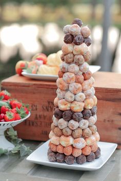 a stack of donuts sitting on top of a white plate next to strawberries