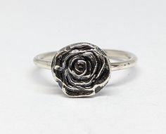 "These are so fun! I made the rose by melting scrap silver (making it into a large molten ball, \"shot\") and hammering it in a shot plate. Similar to using a die and a hydraulic press, but more tired muscles! 😂    The sterling silver band is 14 gauge. Listing is for the exact ring shown, size 7.  All components are sterling silver. Lovestruck Soul - a one woman in-home jewelry studio, creating hand fabricated jewelry one piece at a time with love, a hammer, and a torch." Adjustable Sterling Silver Jewelry In Rose Color, Adjustable Rose Sterling Silver Jewelry, Adjustable Sterling Silver Flower Ring With Rose Design, Adjustable Sterling Silver Rose Design Ring, Sterling Silver Rose Design Flower Ring, Chunky Silver Rose Ring, Vintage Hand-cast Skull Ring For Gift, Handmade Silver Skull Ring, Symbolic Style, Nickel-free Sterling Silver Skull Ring