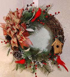 a christmas wreath hanging on the wall next to a birdhouse and pine cone decorations