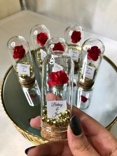 a person holding a bottle filled with gold and red flowers in front of other bottles