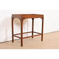 a small wooden table sitting on top of a floor next to a white brick wall