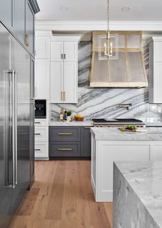 a kitchen with marble counter tops and stainless steel refrigerators, along with white cabinets