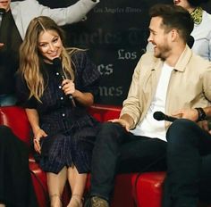 two people sitting on red chairs talking to each other