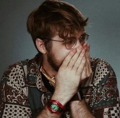 a man wearing glasses covers his face with his hands