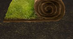 a roll of grass sitting on the ground next to a rolled up piece of wood