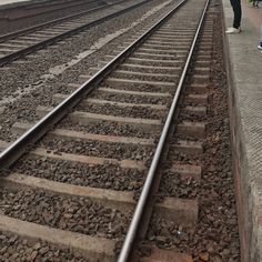 two people are walking on the railroad tracks