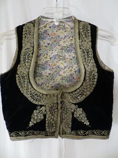 "Gorgeous workmanship on this vintage vest. From a collectors estate. Overall condition very good, some wear and imperfections (see close-ups), loose threads. Likely missing a front button as there are three buttons and a loop that doesn't match up, then two hooks with matching loops. No damage to velvet. Lining intact and unstained. Small size, chest is 33\", 'waist' 28\", length 15.5\". Wonderful historical piece. Please convo with questions." Traditional Black Vest For Festival, Traditional Fitted Black Vest, Traditional Black Sleeveless Vest, Fitted Vintage Vest For Festivals, Traditional Embroidered Festive Vest, Traditional Vest With Intricate Embroidery, Vintage Embroidered Vest For Festivals, Vintage Festival Vest, Traditional Embroidered Fitted Vest