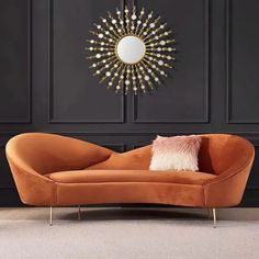 an orange couch sitting in front of a black wall with a wreath on the wall