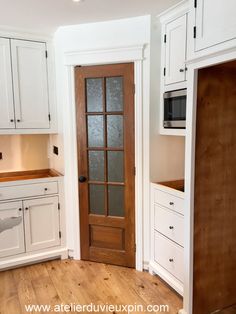 an empty kitchen with white cabinets and wood flooring is seen in this image from the doorway