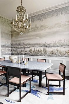 a dining room with a chandelier hanging from the ceiling and a large painting on the wall