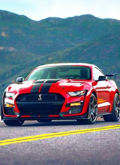 a red and black mustang driving down the road