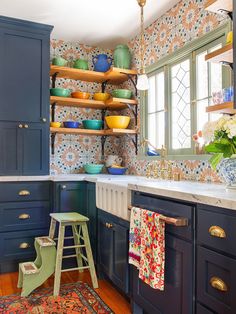 a kitchen with blue cabinets and colorful wallpaper