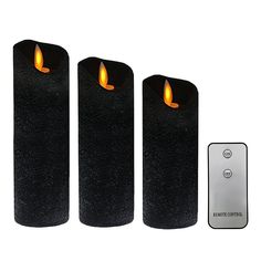 three black candles sitting next to a remote control