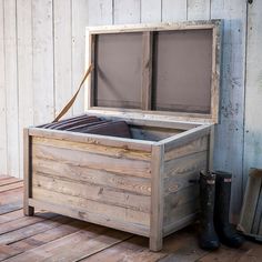 an empty wooden box sitting on top of a wooden floor next to a pair of boots