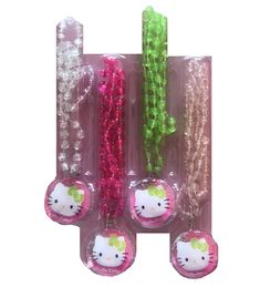 three hello kitty ornaments in plastic packaging on a white background with green and pink beads