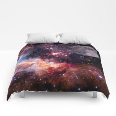 a bed covered in a comforter and pillows with an image of the galactic sky