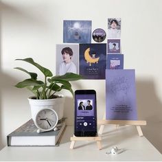 a cell phone sitting on top of a wooden stand next to a plant and pictures