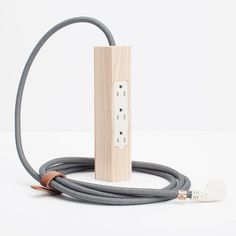 an electrical outlet plugged into a wooden box with two cords attached to it and a white wall in the background