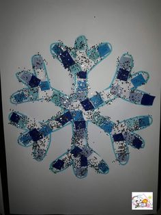 a snowflake made out of blue and silver glitters on a white wall