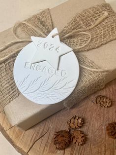 a white ornament sitting on top of a wooden table next to some pine cones