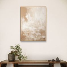 a painting hanging on the wall above a wooden table with shoes and plant in it