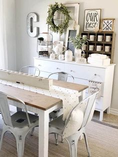 a dining room table with chairs and pictures on the wall above it, in front of a white dresser