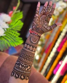 a henna tattoo on someone's hand with flowers in the background