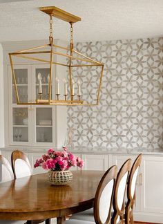 a dining room table with white chairs and a chandelier hanging from the ceiling