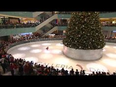 a large christmas tree is in the middle of an ice rink as people look on