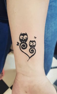 an owl tattoo on the wrist with two smaller owls in it's heart shape