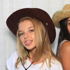 two beautiful young women standing next to each other wearing hats on their heads and smiling at the camera