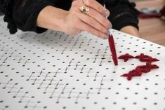 a woman is doing something on the table with red thread and crochet hooks