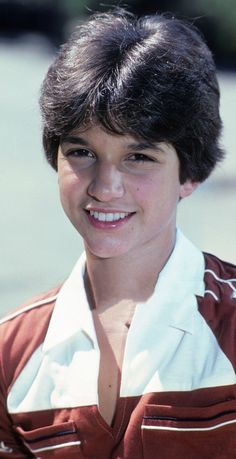 the young boy is wearing a red and white shirt with his hair in a pimpy style