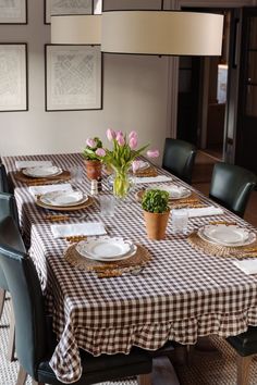 a dining room table set for four with place settings and flowers in vases on the table