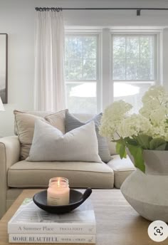 a living room with a couch, coffee table and vase filled with flowers on top of it